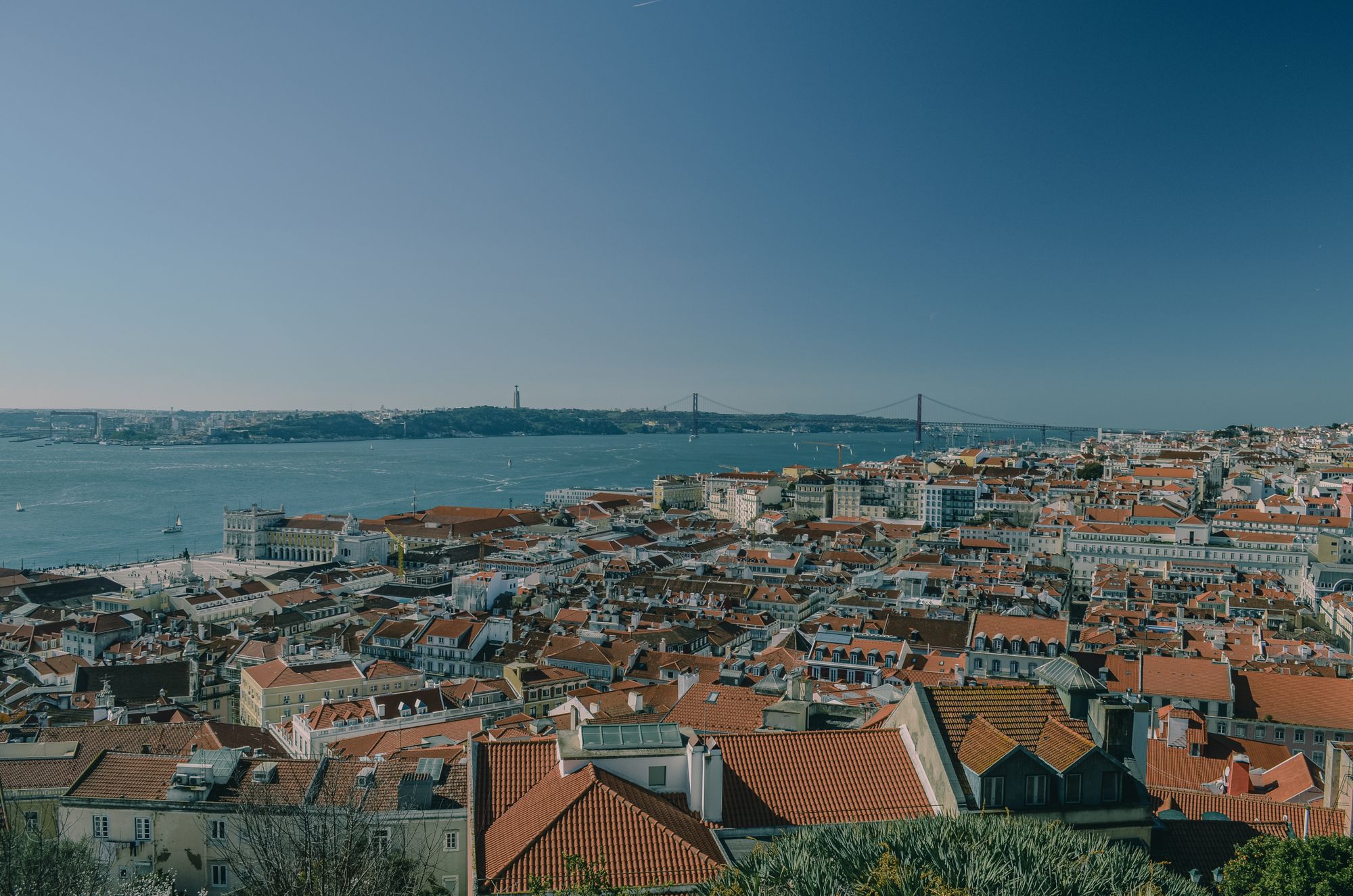 Golden-hour view over Lisbon's pastel rooftops toward the Tagus river